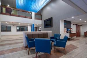 - une salle d'attente avec des chaises bleues et une table dans l'établissement Holiday Inn Express Hotel & Suites Coon Rapids - Blaine Area, an IHG Hotel, à Coon Rapids