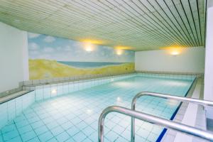 a large swimming pool with a painting on the wall at Gemütliche Wohnung unter Reet mit Pool und Sauna in Keitum in Keitum