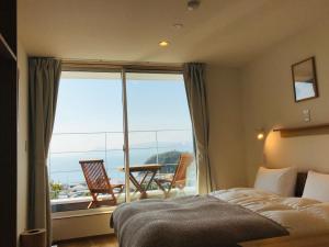 a bedroom with a bed and a balcony with a table and chairs at MY LODGE Naoshima in Naoshima