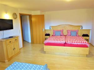 Schlafzimmer mit einem Holzbett mit roten und blauen Kissen in der Unterkunft Sägerhof Bader in Rettenberg