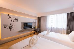 pokój hotelowy z dwoma łóżkami i telewizorem w obiekcie Magnotel Renmin Road City Hall QingYuan w mieście Qingyuan