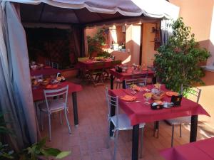 ein Restaurant mit roten Tischen und Stühlen auf einer Terrasse in der Unterkunft Affittacamere Le Statue Del Sinis in Càbras