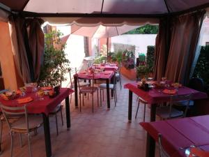 a restaurant with red tables and chairs and an umbrella at Affittacamere Le Statue Del Sinis in Càbras