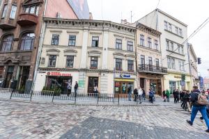 um grupo de pessoas andando por uma rua com edifícios em 2 Kn. Romana Apartment em Lviv