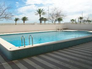 una piscina accanto a un muro bianco con palme di ALMIRANTE Vista al mar - Alquiler familias a Playa de Gandia