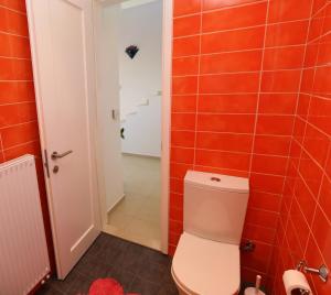 uma casa de banho com WC e azulejos vermelhos em Entire independent maisonette near Heraklion Pottery Classes em Petrokefalo