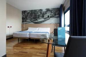 a hotel room with a bed, table, chair and window at Aparthotel Campus in Oviedo