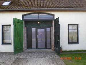 an open door of a white house with green doors at Ferienhaus Weitblick in Börgerende-Rethwisch
