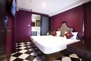 een slaapkamer met een groot wit bed met paarse muren bij Violet Tower at Khaosan Palace in Bangkok
