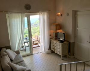 Una sala de estar con un sofá y un televisor y un balcón. en BnB Borgo le Vigne - La Barrique Only Adults, en Tignale