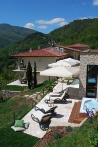 een patio met parasols, ligstoelen en een zwembad bij BnB Borgo le Vigne - La Vendemmia in Tignale