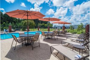 um pátio com mesas e guarda-sóis ao lado de uma piscina em Holiday Inn Express Hotel & Suites West Monroe, an IHG Hotel em West Monroe