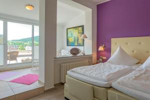 ein Schlafzimmer mit einem Bett und einer lila Wand in der Unterkunft Hotel Koch Schilt in Irrel