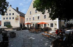 un grupo de mesas y bancos frente a un edificio en Brauerei-Gasthof Eck, en Böbrach