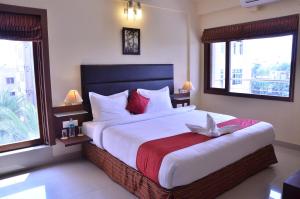 a bedroom with a large bed and two windows at LBD RESORTS & HOTELS KOLKATA in Kolkata