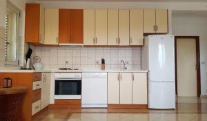 een keuken met witte apparaten en houten kasten bij Bodul Vacation Apartment in Zaton