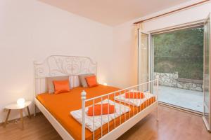 een slaapkamer met een bed met oranje kussens en een raam bij Bodul Vacation Apartment in Zaton