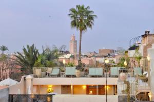 vistas a un edificio con sillas y palmeras en Riad Anjar en Marrakech