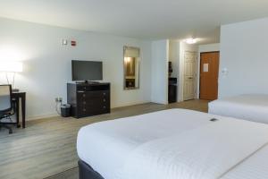 a bedroom with two beds and a desk and a television at Holiday Inn Hotel & Suites Bloomington Airport by IHG in Bloomington
