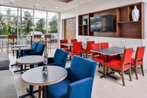 Holiday Inn Express & Suites - Siloam Springs, an IHG Hotel في Siloam Springs: مطعم به طاولات وكراسي وتلفزيون