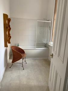 a bathroom with a bath tub and a chair in it at The Georgian House in Glasgow