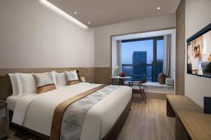 a bedroom with a large bed and a large window at Somerset Zhongmao Changchun in Changchun