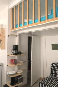 a loft bed in a tiny room with a kitchen at Maisonnette studio sur cour in Paris