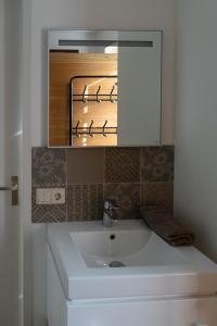 ein Badezimmer mit einem weißen Waschbecken und einem Spiegel in der Unterkunft Nieuw: Kom in de Bedstee Uniek! in Winterswijk