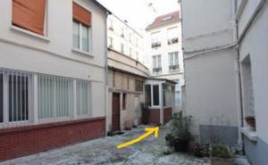 a yellow arrow in an alley between two buildings at Maisonnette studio sur cour in Paris