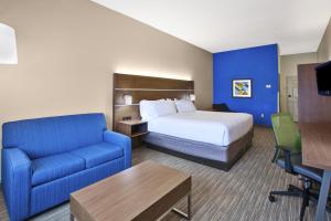 a hotel room with a bed and a blue couch at Holiday Inn Express Hotel & Suites Manchester Conference Center by IHG in Manchester