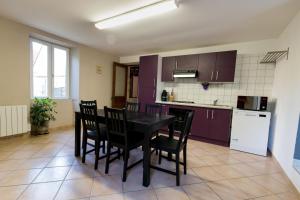 a kitchen with a black table and black chairs at La ferme de Fumichon in Tour-en-Bessin