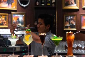 a man is preparing cocktails in a bar at La Seine Hotel in Vientiane