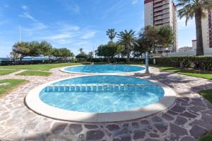 une piscine dans un parc arboré et un bâtiment dans l'établissement AG MANILA PREMIUM, à Playa de Gandia