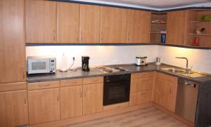 - une petite cuisine avec des placards en bois et un four micro-ondes dans l'établissement Ferienwohnung Rothirsch, à Bad Sachsa