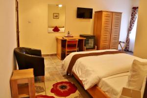 a bedroom with a bed and a desk and a television at Eden Vale Hotel in Ajiringano