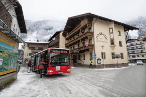 Ein roter Bus steht auf einer schneebedeckten Straße. in der Unterkunft Hotel Untermetzger in Zell am Ziller