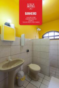 a bathroom with a sink and a toilet and a sign at Cheri Ami Hotel in Joinville