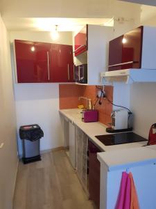 eine Küche mit weißen Arbeitsflächen und roten Schränken in der Unterkunft appartement renové , quartier historique du panier , centre-ville in Marseille