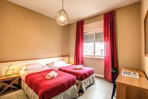 2 łóżka w pokoju z czerwonymi zasłonami w obiekcie City Guest House w Rzymie