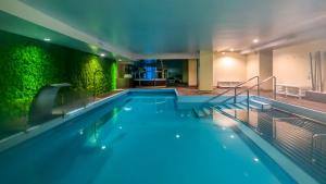 a swimming pool in a building with a green wall at Hotel Lodomar Spa & Talasoterapia in San Pedro del Pinatar