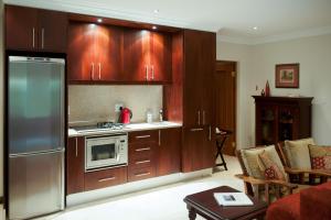 a kitchen with wooden cabinets and a stainless steel refrigerator at Blaauwheim Guest House in Somerset West