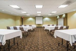 une salle de conférence avec des tables et des chaises blanches et un écran dans l'établissement Holiday Inn Express Hotel & Suites El Dorado, an IHG Hotel, à El Dorado