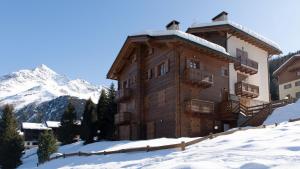 um grande edifício de madeira na neve com uma montanha em Italianway - Meralda 2 em Santa Caterina di Valfurva