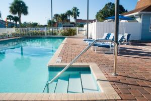 a swimming pool with two chairs and an umbrella at Villas at Fortune Place in Kissimmee
