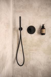 a shower with a black shower head on a wall at OKU Kos in Marmari