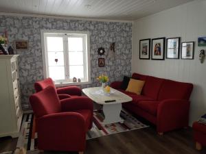 una sala de estar con 2 sillas rojas y una mesa. en Kårboligen en Bøstad