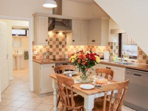 a kitchen with a table with a vase of flowers on it at Oakland Cottage in Craven Arms