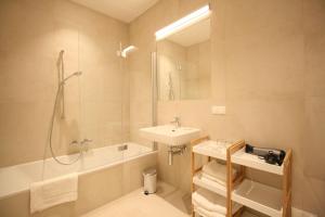 La salle de bains est pourvue d'un lavabo, d'une baignoire et d'une douche. dans l'établissement Your Living Vienna CBD, à Vienne