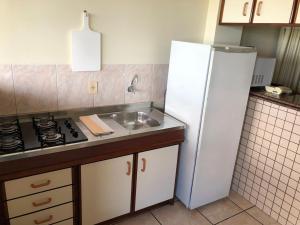 a kitchen with a white refrigerator and a sink at Hotel Residencial Itapema in Itapema