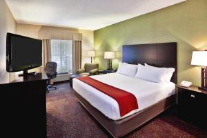 a hotel room with a bed and a flat screen tv at Holiday Inn Express Hotel & Suites Woodhaven, an IHG Hotel in Woodhaven